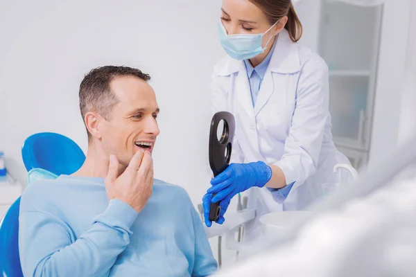 亲切的牙医拿着镜子, 而病人看着他的牙齿 — 图库照片