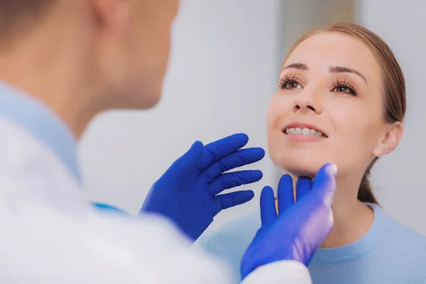 Mujer feliz sonriendo mientras el dentista mira sus aparatos ortopédicos — Foto de Stock