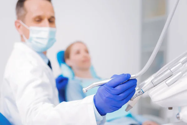 Dentiste professionnel utilisant une perceuse dentaire tout en aidant son patient — Photo