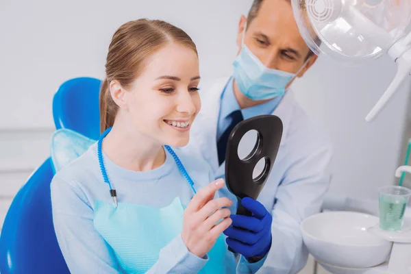 Kalm tandarts kijken naar zijn patiënt bewonderen nieuwe bretels — Stockfoto