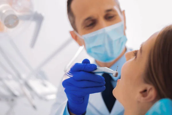 Dentista alegre segurando cuidadosamente equipamentos odontológicos enquanto trabalhava — Fotografia de Stock
