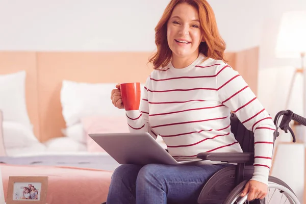 Feliz mujer inmóvil bebiendo té — Foto de Stock