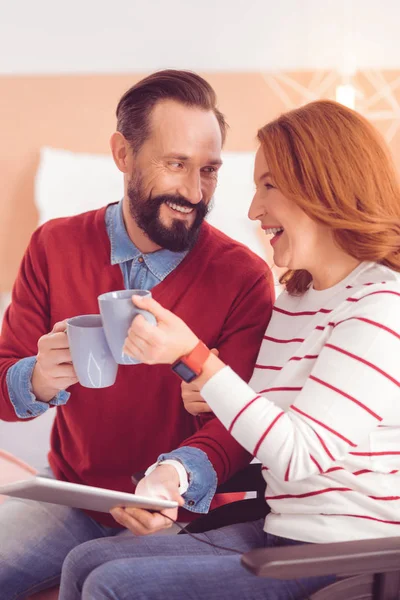 Positive mid aged couple drinking tea at home