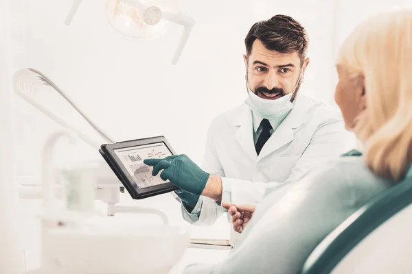 Dentista sosteniendo el comprimido y hablando con el paciente —  Fotos de Stock