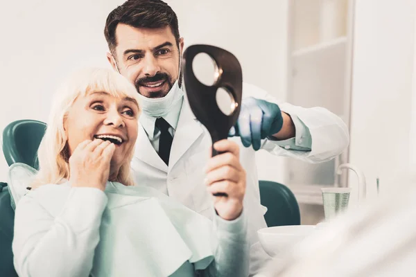 Senior kobieta siedzi w Fotel dentystyczny i patrząc w lustro — Zdjęcie stockowe