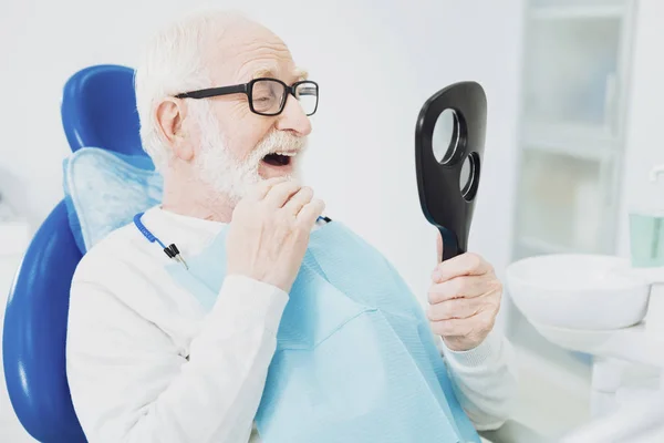 Aantrekkelijk senior man evaluatie van zijn tanden — Stockfoto