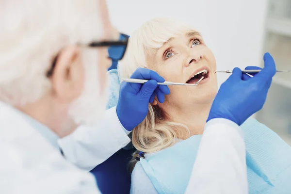 Dentista masculino atento que comprueba los dientes de mujer —  Fotos de Stock