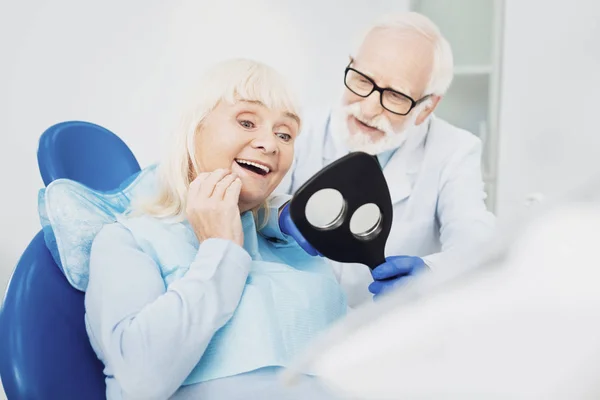 Überschwängliche Seniorin prüft ihre Zähne — Stockfoto