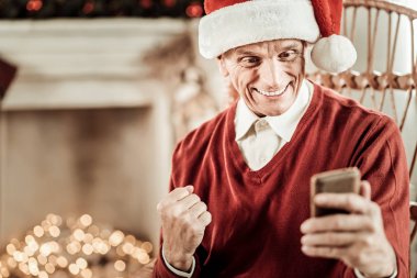 Sevindirici ve cep telefonunu tutan şaşırmış adam memnun.