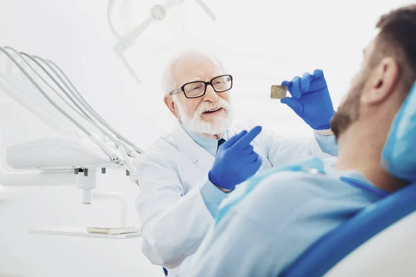 Thoughtful male dentist interpreting teeth radiography — Stock Photo, Image