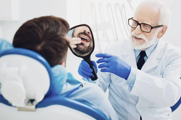 Odontólogo masculino profesional dando espejo al paciente — Foto de Stock