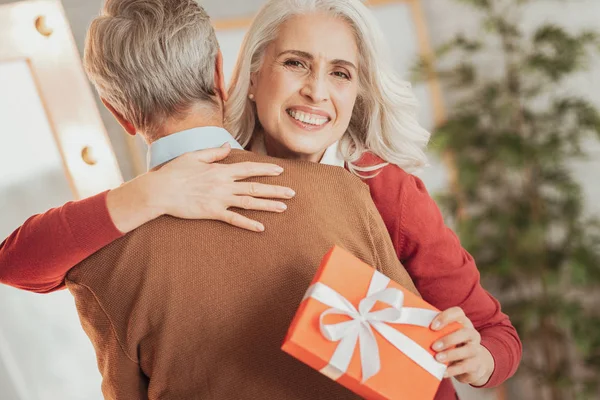 Encantada mujer mayor recibiendo felicitaciones de su marido . — Foto de Stock