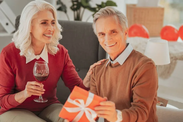 Старша пара сидить в келихах червоного вина і подарунок — стокове фото