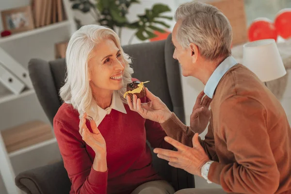 Ältere Dame nimmt einen Kuchen von ihrem Mann — Stockfoto