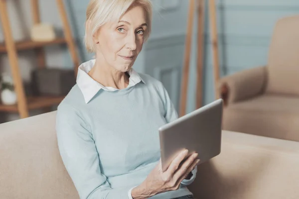 Mujer de edad agradable sosteniendo su tableta — Foto de Stock