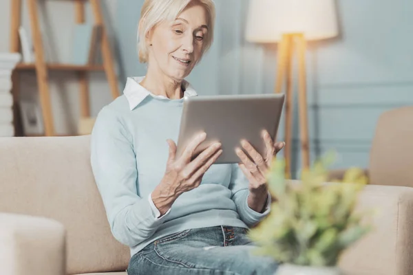 Příjemný starší žena při pohledu na obrazovku tabletu — Stock fotografie
