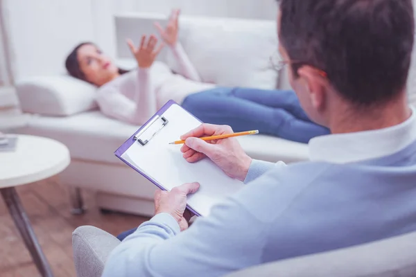 Achteraanzicht van geconcentreerde psycholoog noodzakelijk notities maken — Stockfoto