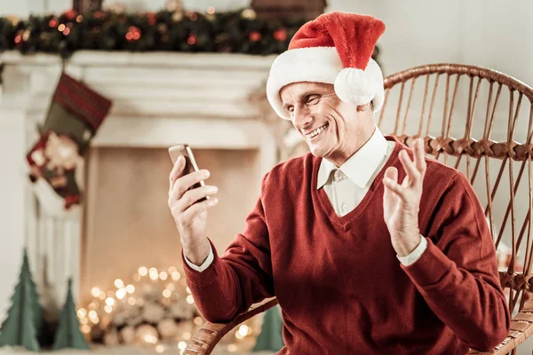 Hombre anciano satisfecho sosteniendo el teléfono celular y estrechando la mano . — Foto de Stock