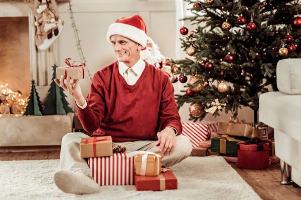 Senior joyful man sitting and overlooking gifts. — Stock Photo, Image