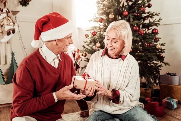 Atento hombre agradable sentado y dando un regalo . — Foto de Stock