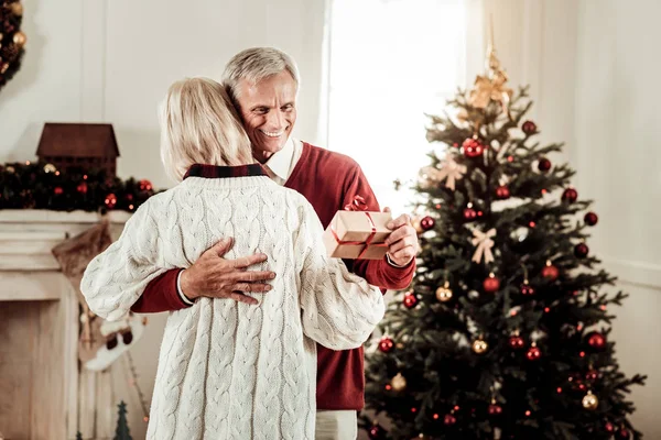 Joyful lycklig man kramar sin fru och hålla en present. — Stockfoto