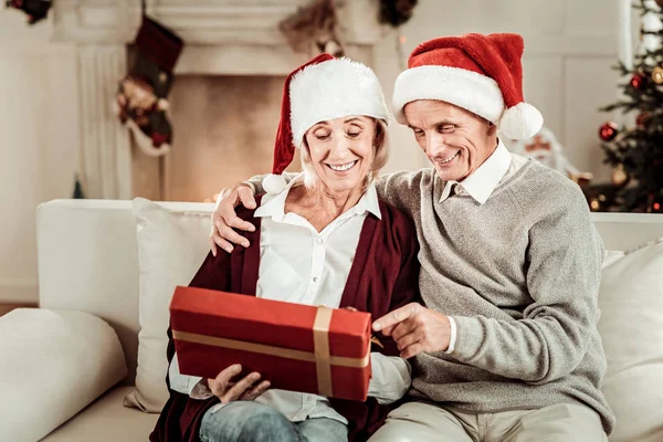 Alegre pareja mayor sentada y sosteniendo un regalo . — Foto de Stock