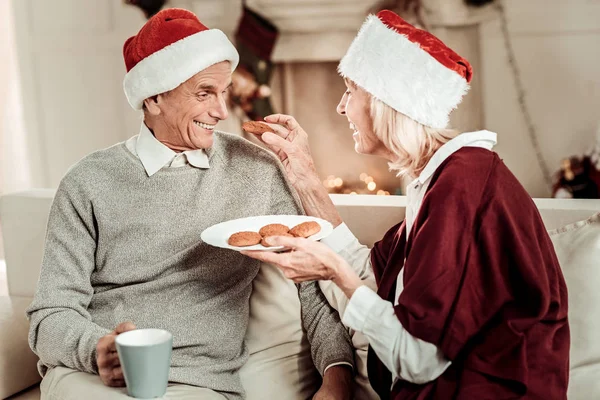 Sorprendido hombre agradable sosteniendo una taza y mirando la torta . — Foto de Stock