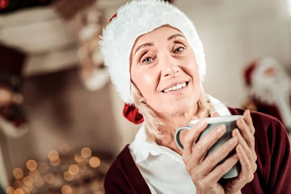 Trevlig äldre kvinna håller en kopp och leende. — Stockfoto