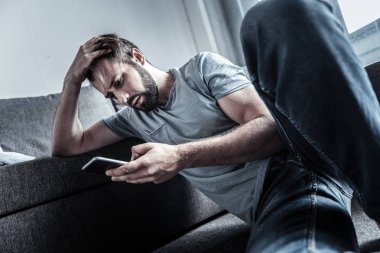 Kötü haber. Low-Spirited sakallı erkek antrenöre yaslanmış ve mesajý okurken kafa selam