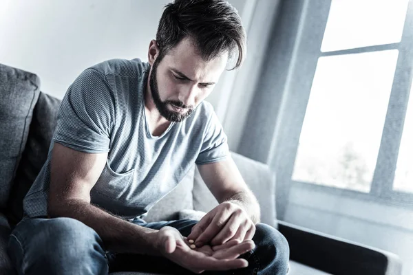 Upset bearded man going th eat pills — Stock Photo, Image