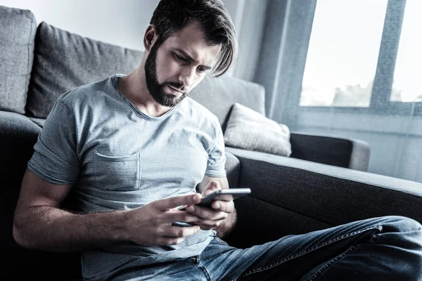 Low-spirited male person looking at his telephone — Stock Photo, Image