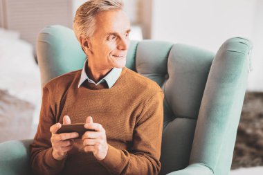 Evde turkuaz deri koltukta oturan yaşlı adam