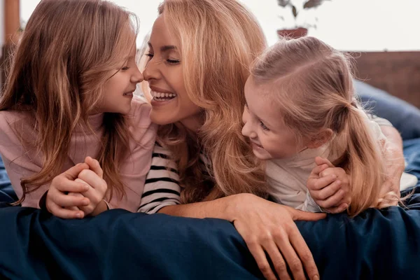 Glada kvinna om på sängen med döttrar — Stockfoto