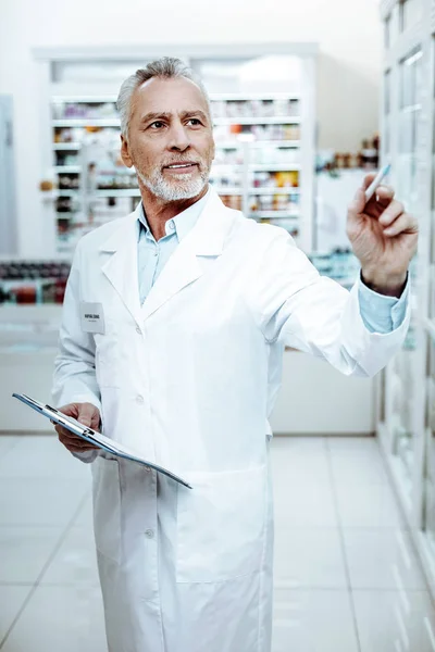 Προσεκτικός γενειοφόρος άνδρας στέκεται στη μέση του φαρμακείου — Φωτογραφία Αρχείου
