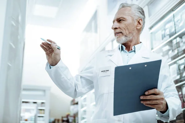 Glada gråhårige mannen tittar uppmärksamt på medicin — Stockfoto