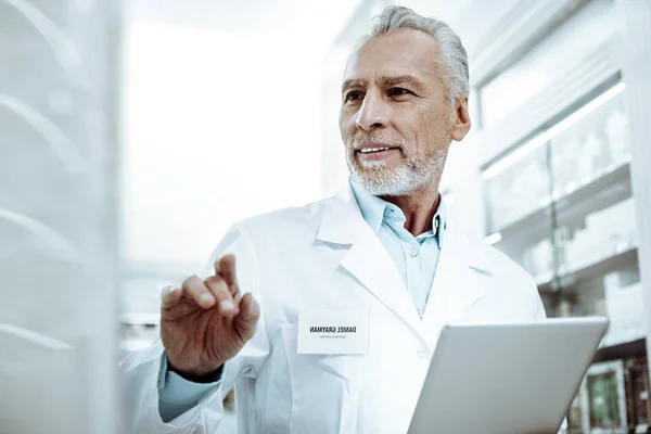 Positiv henrykt eldre mann som ser på medisin – stockfoto