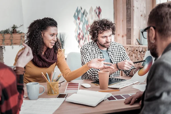 Positive delighted curly-haired woman pointing at palette — Stock Photo, Image