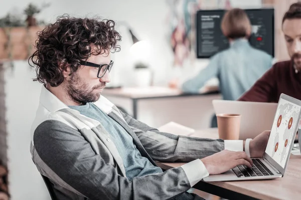 Geconcentreerde curly-haired man aan het werk op zijn laptop — Stockfoto