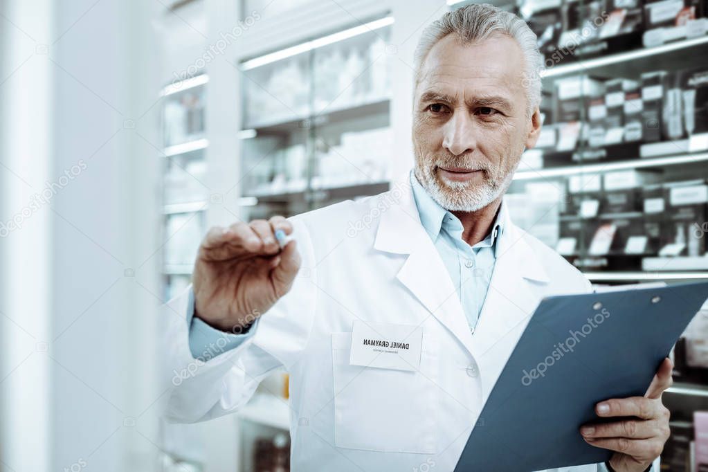 Attentive senior pharmacist working consciously in drugstore