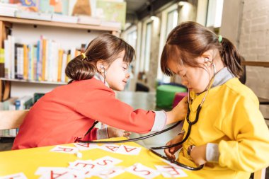 Şirin esmer güneşli çocuk kız kardeşi ile oynarken gülümseyen