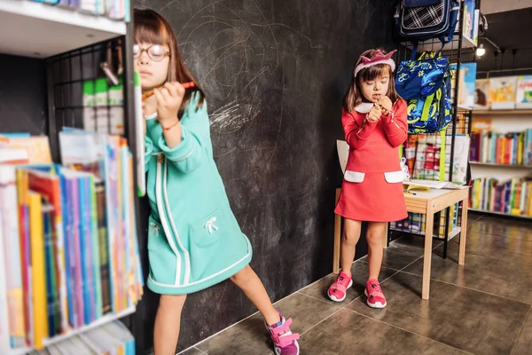 Linda hermana agradable con vestido rojo de pie cerca de su hermana — Foto de Stock