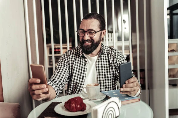 Pozitivní vousatých korálek držení dvou smartphonů ve stejné době — Stock fotografie