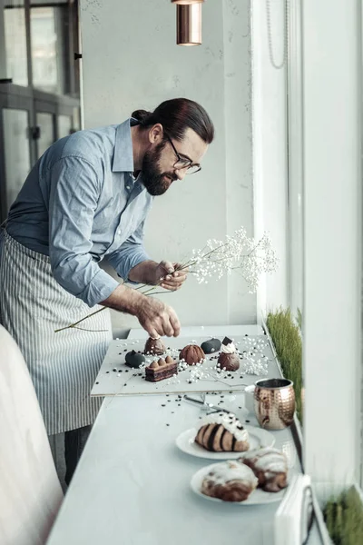 Ernsthafter smarter Mann dekoriert einen Teller mit Kuchen — Stockfoto