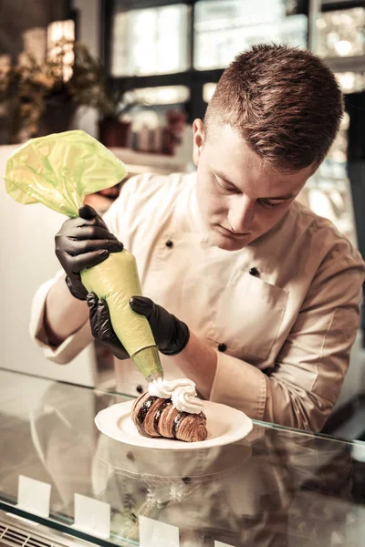 Bel giovanotto che finisce una preparazione di croissant — Foto Stock