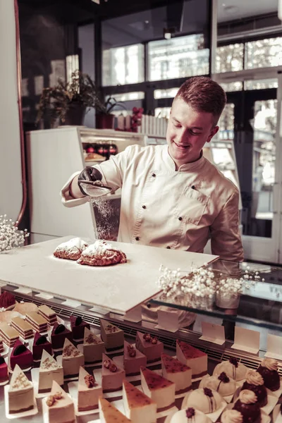 Joyeux chef pâtissier positif utilisant de la poudre de sucre — Photo