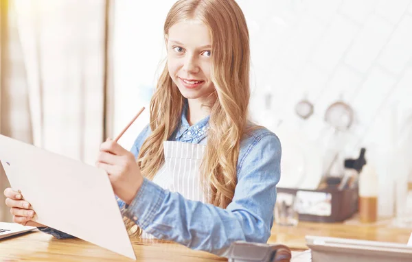 Joyeux jeune femme regardant dans la caméra tout en travaillant dans le café — Photo