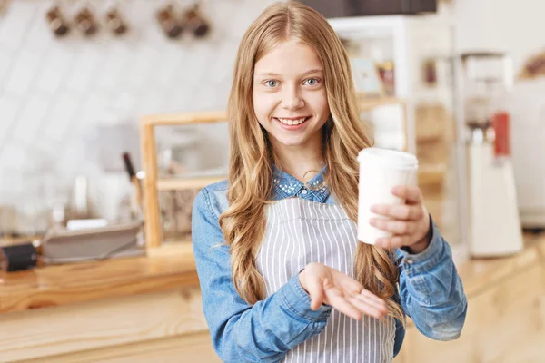 Chica alegre radiante en la cámara mientras propone una taza de café —  Fotos de Stock