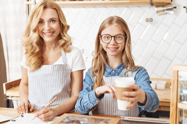 Beaming mother and daughter smiling to client in cafe