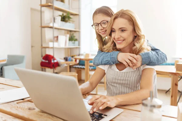 Doordachte tienermeisje omarmen haar moeder die op laptop werkt — Stockfoto