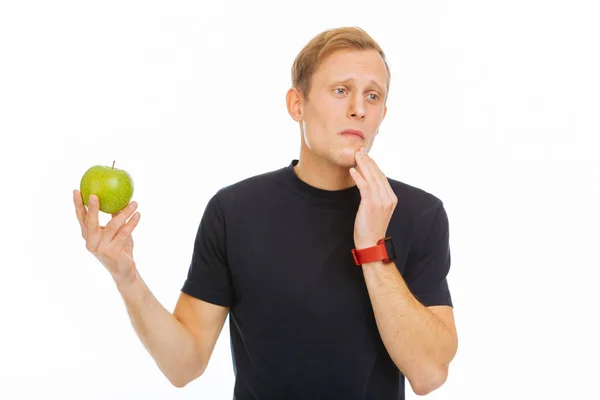 Pleasant sad man holding a green apple — Stock Photo, Image